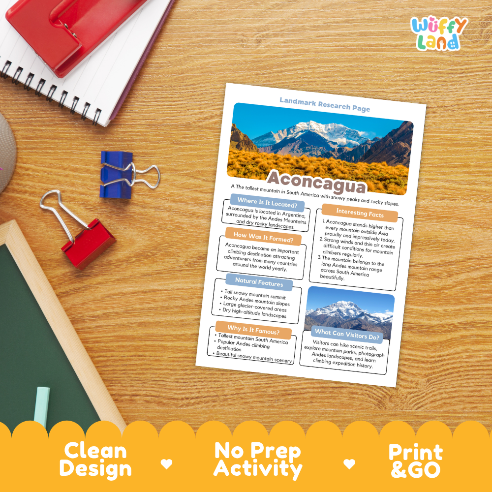 A printed 'Landmark Research Page' titled 'Aconcagua' lies on a wooden desk, surrounded by school supplies including a spiral notebook, binder clips, and a red notebook. The page features a landscape photo of snow-capped mountains and text sections.