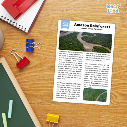 A printed educational poster titled 'Amazon Rainforest' laid on a wooden desk, surrounded by school supplies including a spiral notebook, red and blue binder clips, a green folder, and a pencil. The poster includes two small rainforest photos and descriptive text.