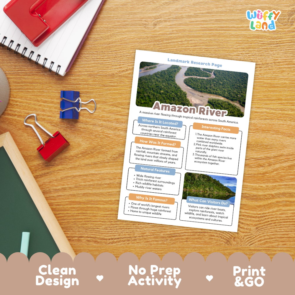 A printed Amazon River landmark research page laid on a wooden desk, surrounded by school supplies including a spiral notebook, binder clips, a pencil, and a red folder. The page has colorful text blocks, a river photo, and the title 'Landmark Research Page' with 'Amazon River' prominently displayed.