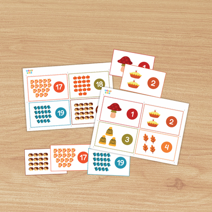 Set of printable counting cards on a wood background featuring autumn icons—mushroom, apple pies, leaves, trees, hedgehogs, foxes, and books. Each card shows a group of items with a large numeral in a colored circle (e.g., 1, 2, 8, 9, 17, 19), designed to practice counting numbers 1–20.