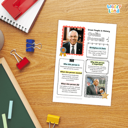 A printed educational poster about Colin Powell laid on a wooden desk, surrounded by school supplies including a spiral notebook, binder clips, chalk, and a red folder.