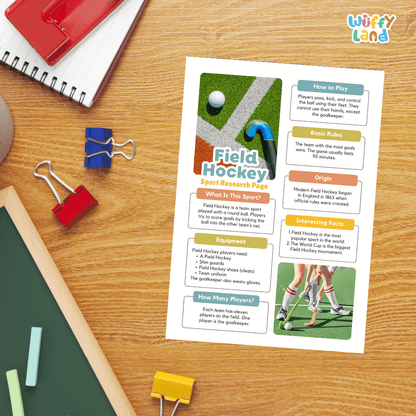 A printed educational worksheet titled 'Field Hockey Sport Research Page' laid on a wooden desk, surrounded by school supplies including a red notebook, blue binder clips, a green chalkboard, and a red pencil. The worksheet features text boxes, a small field hockey graphic, and a player photo.