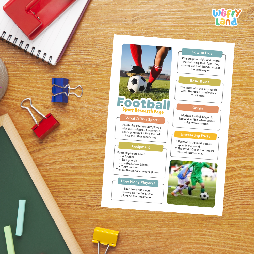 A printed educational poster about football sports research page laid on a wooden desk, surrounded by school supplies including a red spiral notebook, blue and red binder clips, chalk, and a green board.