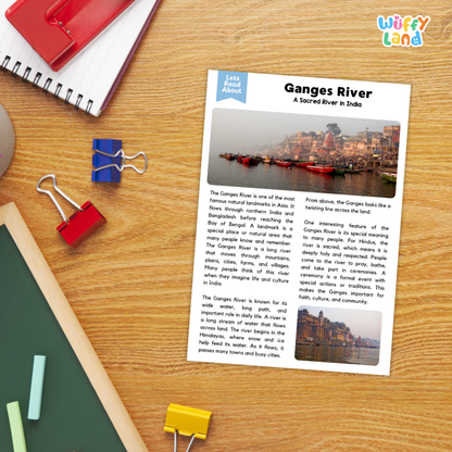 A printed educational poster about the Ganges River laid on a wooden desk with school supplies around it, including a red notebook, blue and red binder clips, a green folder, and yellow paper clips.