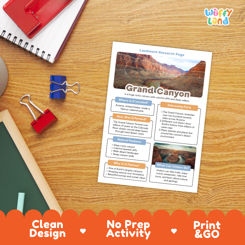 A printed Grand Canyon landscape research page laid on a wooden desk, surrounded by school supplies including a red notebook, blue binder clips, a green chalkboard, and an orange promotional banner at the bottom. The page has a clean design with a canyon photo and text sections.