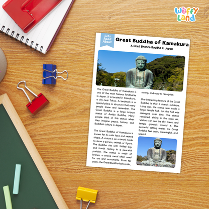 A printed educational poster titled 'Great Buddha of Kamakura' laid on a wooden desk, surrounded by school supplies including a spiral notebook, red and blue binder clips, a green folder, and a red notebook. The poster includes two photos of a Buddha statue and a short article about the statue in Japan.