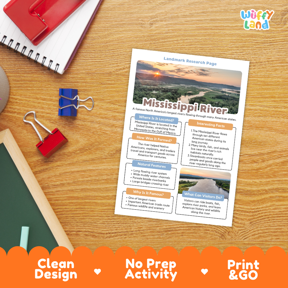 A printed Mississippi River landmark research page laid on a wooden desk, surrounded by school supplies including a spiral notebook, binder clips, and a chalkboard. The page has a scenic river landscape photo and text sections.