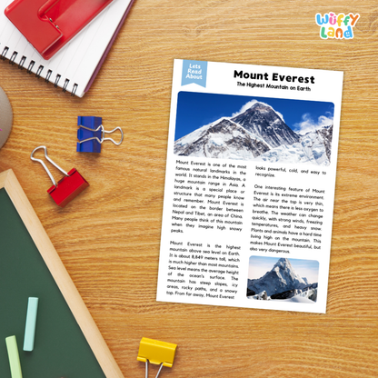 A children's educational poster about Mount Everest laid flat on a wooden desk with school supplies around it, including a spiral notebook, binder clips, a green folder, and a red notebook. The poster has a blue header reading 'Let's Learn About' and the title 'Mount Everest' with descriptive text and two small mountain photos.