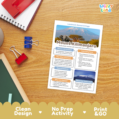 A printed Mount Kilimanjaro landmark research page laid on a wooden desk, surrounded by school supplies including a spiral notebook, red and blue binder clips, and a chalkboard. The page has colorful text boxes and a mountain photo at the top.