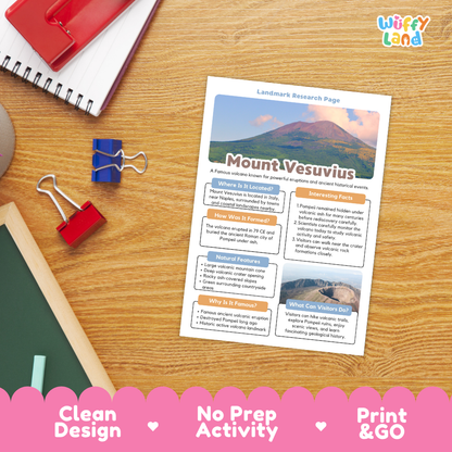 A printed Mount Vesuvius landmass research page laid on a wooden desk, surrounded by school supplies including a spiral notebook, binder clips, and a red folder. The page has colorful headings, text blocks, and a mountain photo.