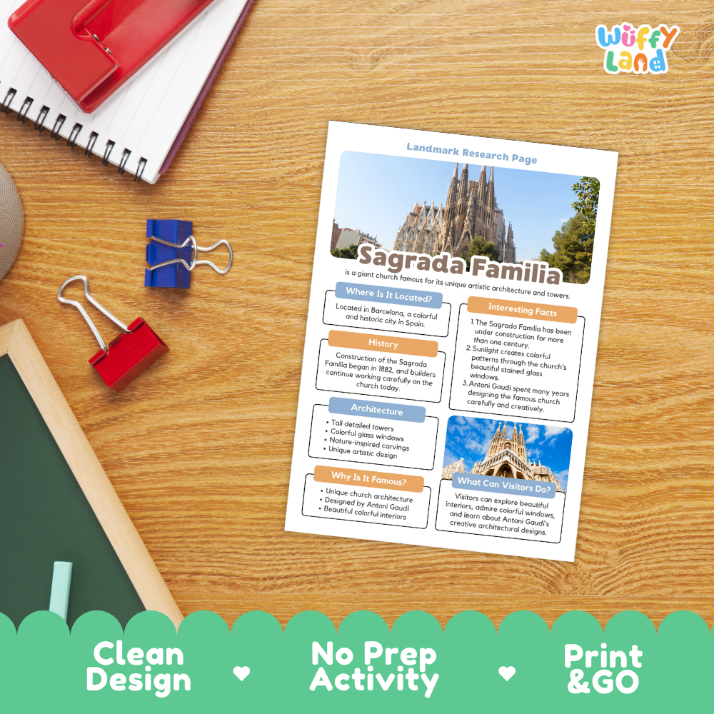 A printed activity sheet titled 'Sagrada Familia' lies on a wooden desk, surrounded by school supplies including a red notebook, binder clips, and a chalkboard. The sheet includes a photo of the cathedral and text blocks for writing.
