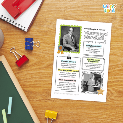 A children's educational poster about Thurgood Marshall laid on a wooden desk, surrounded by school supplies including a spiral notebook, binder clips, chalk, and a red notebook.