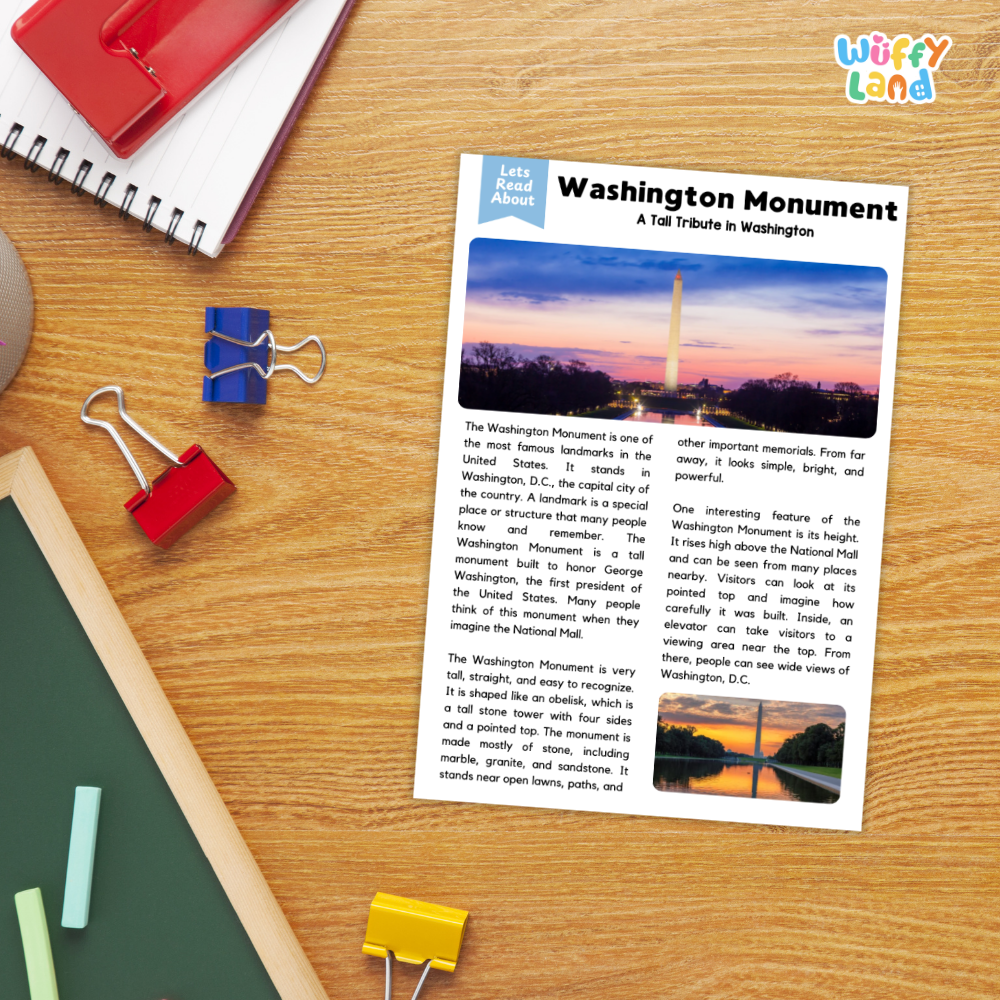 A printed article titled "Washington Monument: A Tall Tribute in Washington" laid on a wooden desk, surrounded by school supplies including a spiral notebook, red binder clips, a green folder, and a blue pen. The article features a photo of the Washington Monument at sunset and a small landscape photo near the bottom.